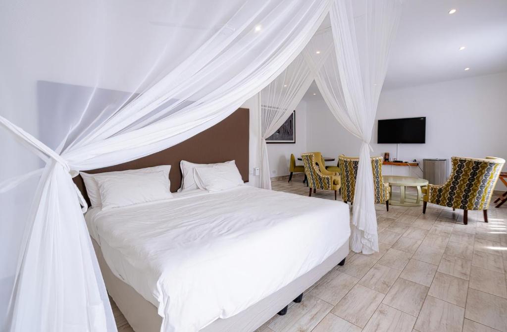 a bedroom with a white bed and a dining room at Lovely deluxe with outdoor pool and gym - 2145 in Victoria Falls