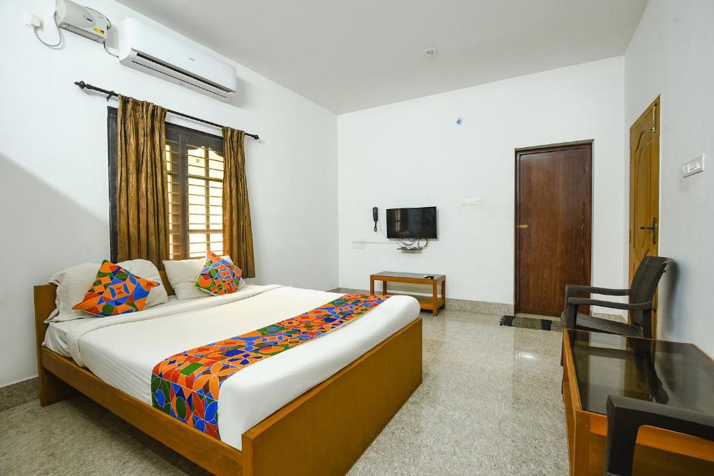 a bedroom with a bed and a desk and a television at FabHotel Joy's Residency in Coimbatore