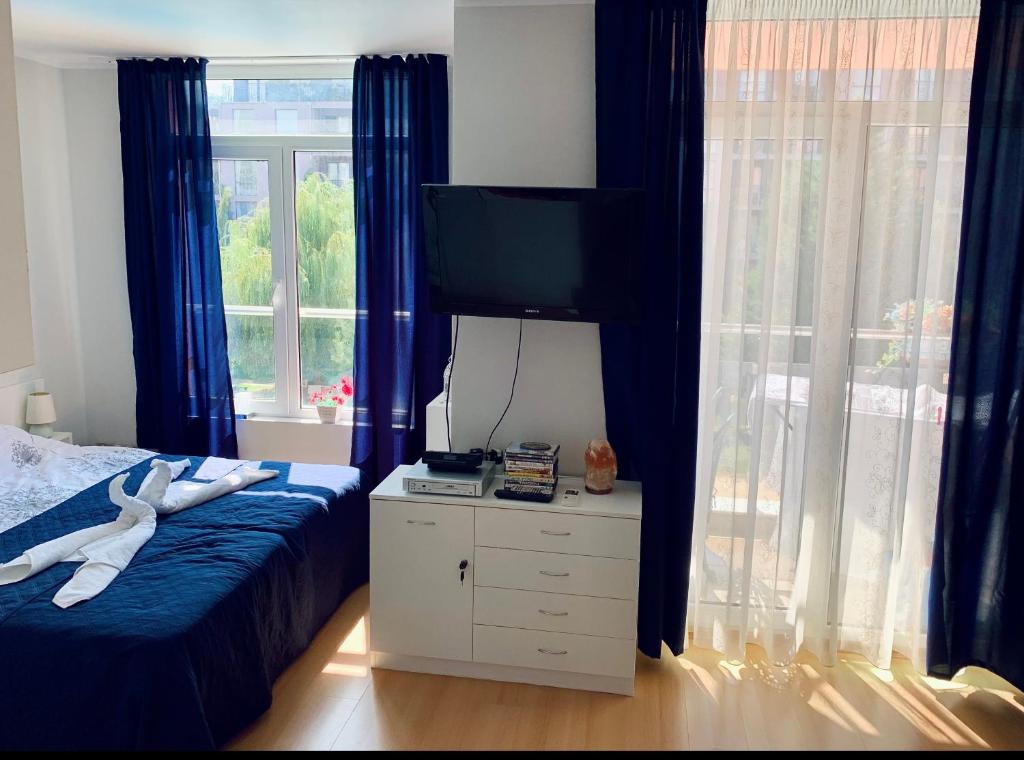 a bedroom with blue curtains and a bed and a television at Apartament Esperanza in Sunny Beach