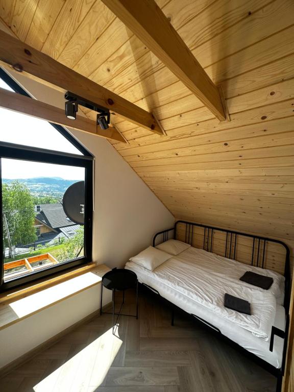 łóżko w pokoju z dużym oknem w obiekcie Domki Jasicówka pod Łysą Górą w Limanowej