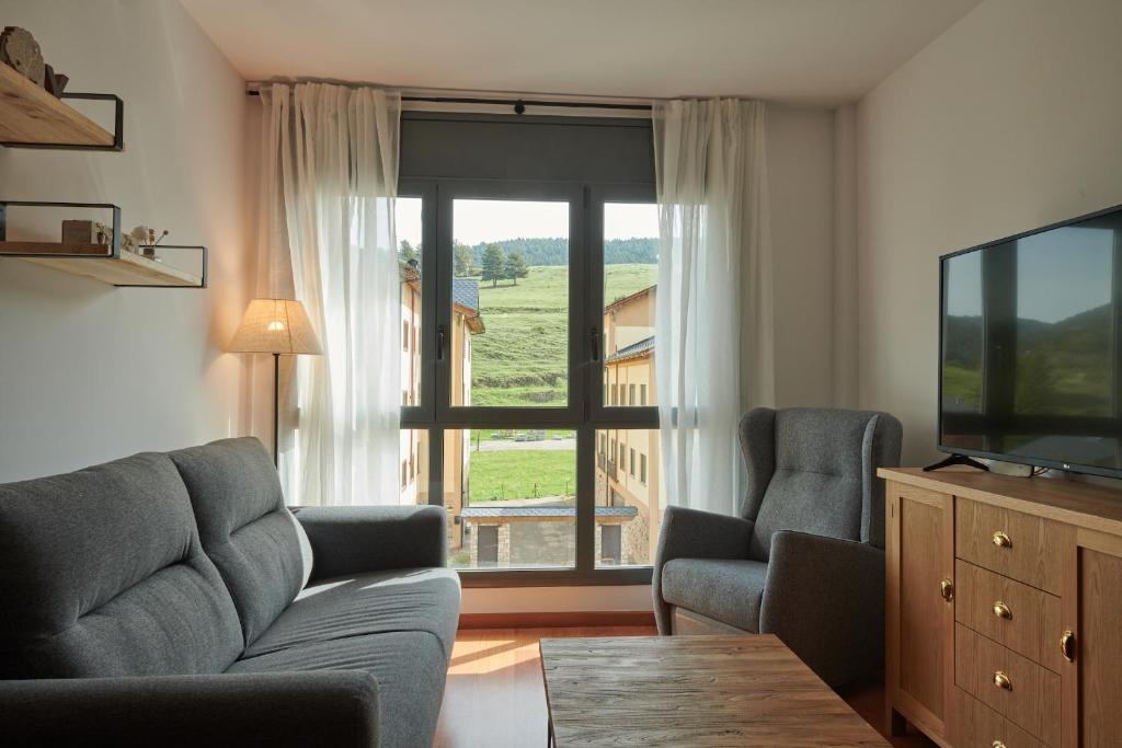 sala de estar con sofá, 2 sillas y TV en Hauzify I Apartament Bella Molina, en Alp