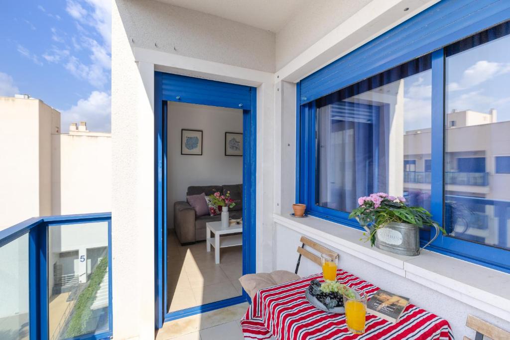 balcón con ventanas azules y mesa con mantel rojo y blanco en Alicante Hills Premium, en Alicante