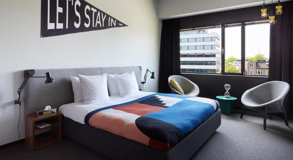 1 dormitorio con 1 cama, 2 sillas y ventana en The Social Hub Amsterdam West 4 star en Ámsterdam
