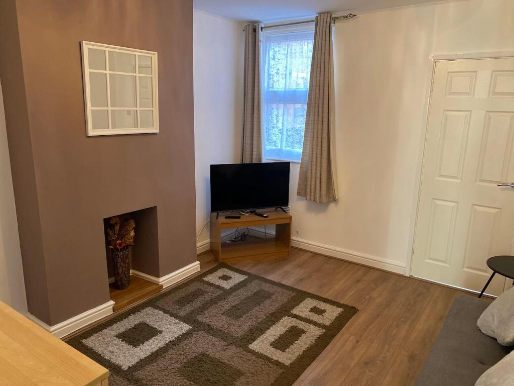 a living room with a fireplace and a television at Isandula House in Nottingham