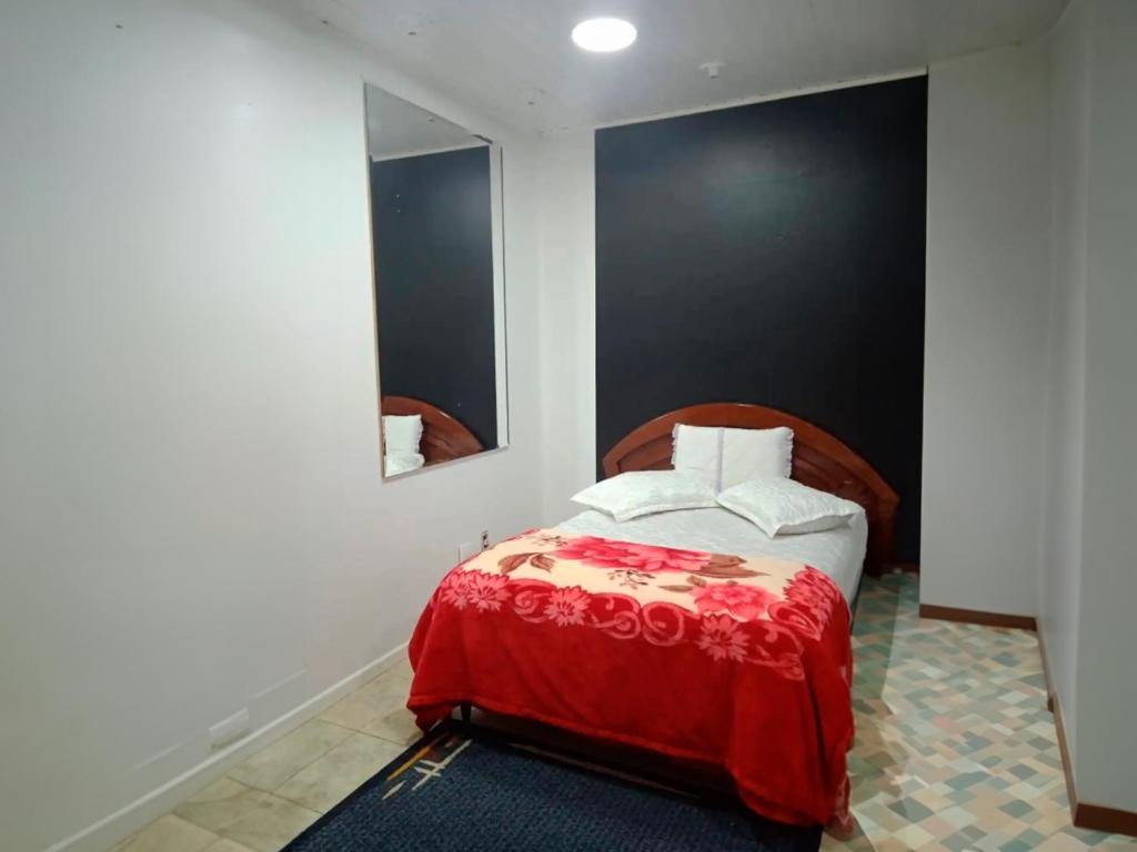 um quarto com uma cama com um cobertor vermelho e um espelho em Pousada Bom Jesus em Ponta Grossa