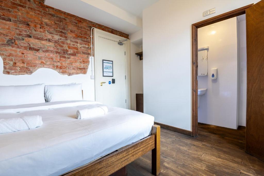 a bedroom with two beds and a brick wall at Palmers Lodge Swiss Cottage in London