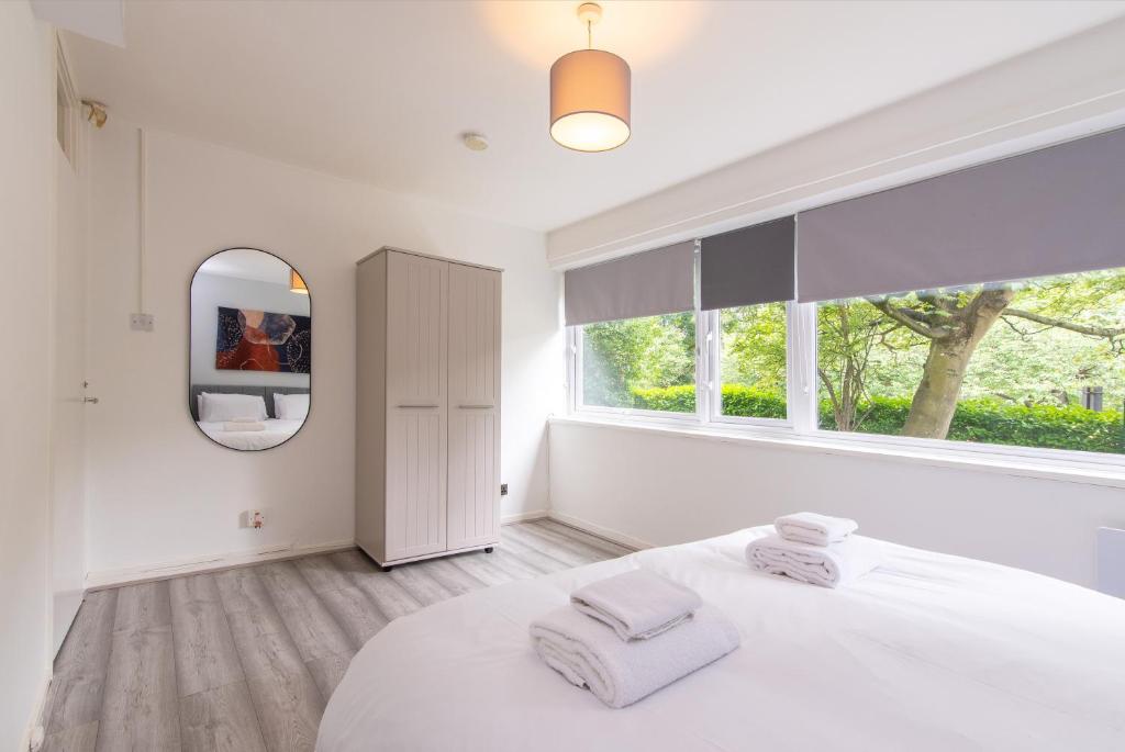 a white bedroom with a large bed and a mirror at Stunning 2 Bedroom Apartments in Birmingham in Birmingham
