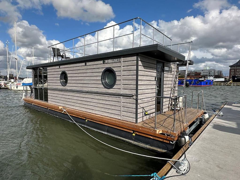 una casa flotante atada a un muelle en el agua en MOLLÖSUND - Hausboot im Herzen von Göteborg en Gotemburgo