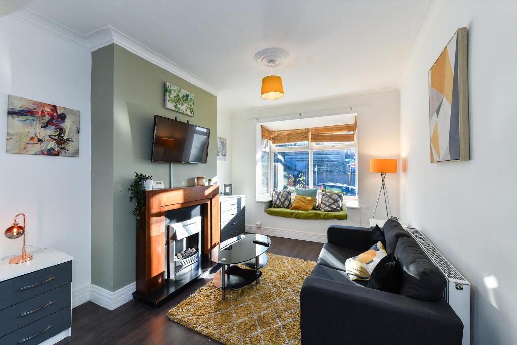 Hillside House في نوتينغهام: غرفة معيشة مع أريكة سوداء وتلفزيون