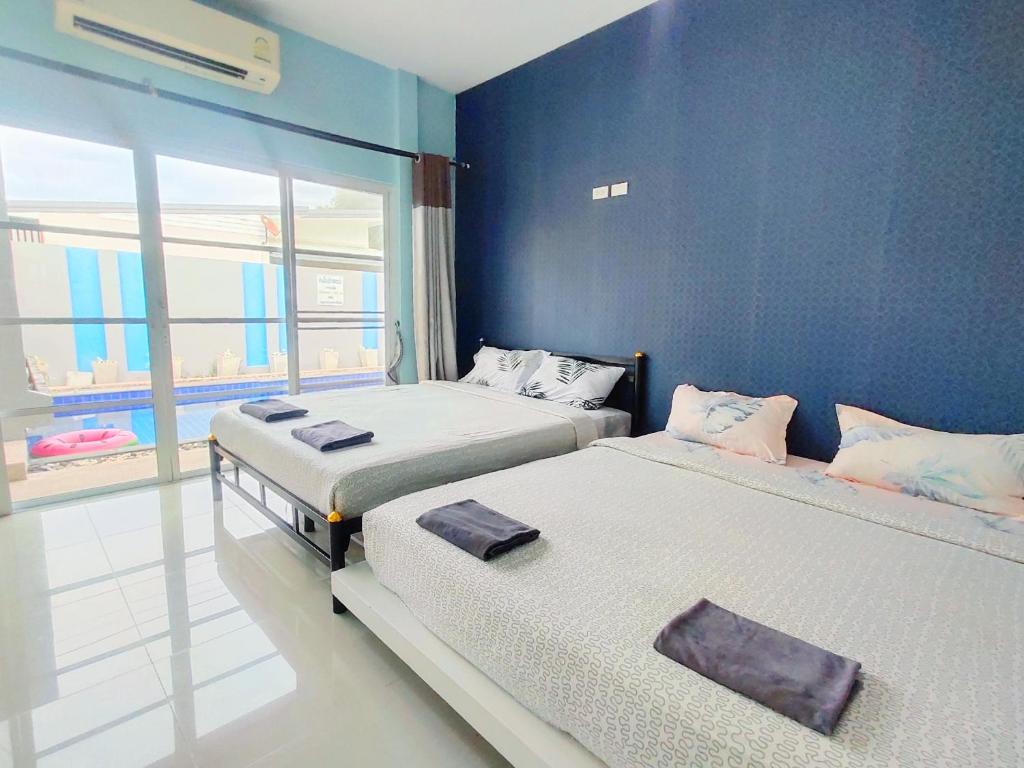 2 letti in una camera con parete blu di อาโป ปาร์ตี้ หัวหิน พลูวิลล่า Apo Party Hua-Hin Pool Villa a Hua Hin
