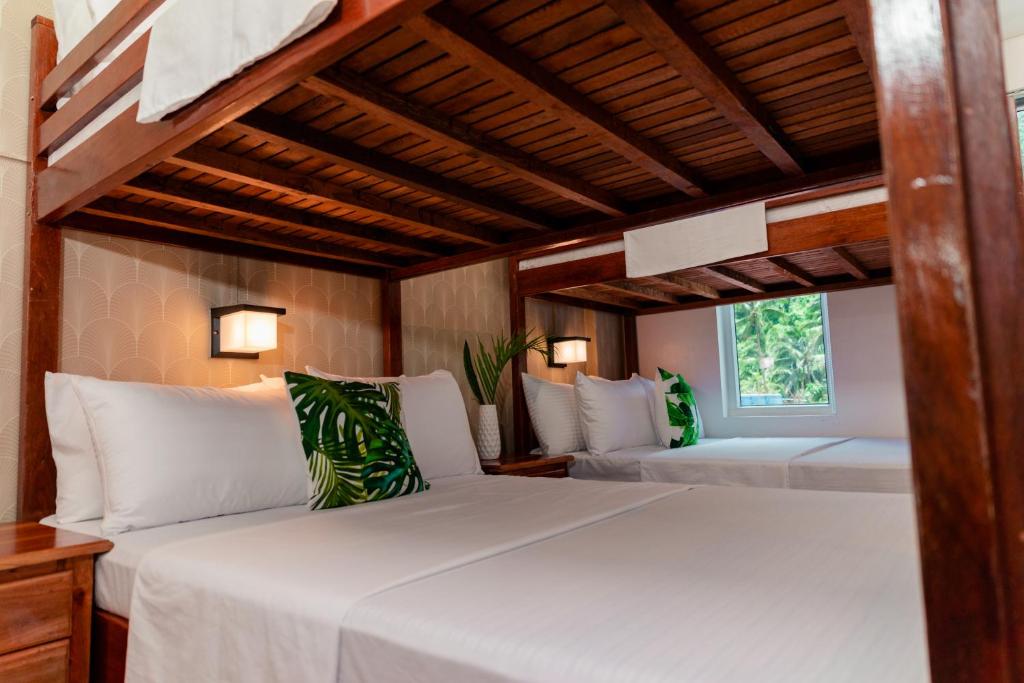 two beds in a room with wooden ceilings at DENGI INN EL NIDO in El Nido