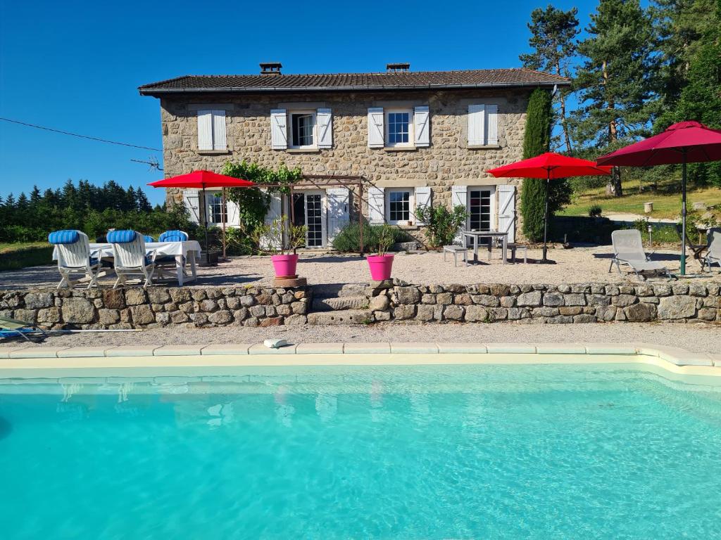 a house with a pool and chairs and umbrellas at Jade room in Saint-Romain-Lachalm