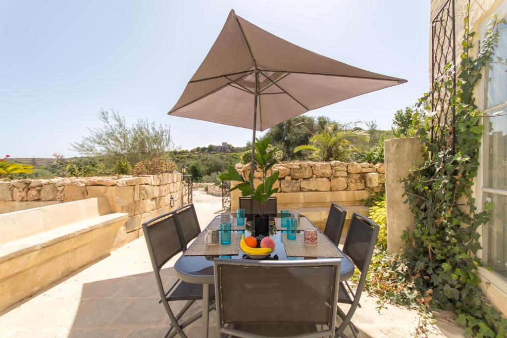 un tavolo con ombrellone su un patio di Pleasant stone house & jacuzzi St Martin - Happy Rentals a Mġarr