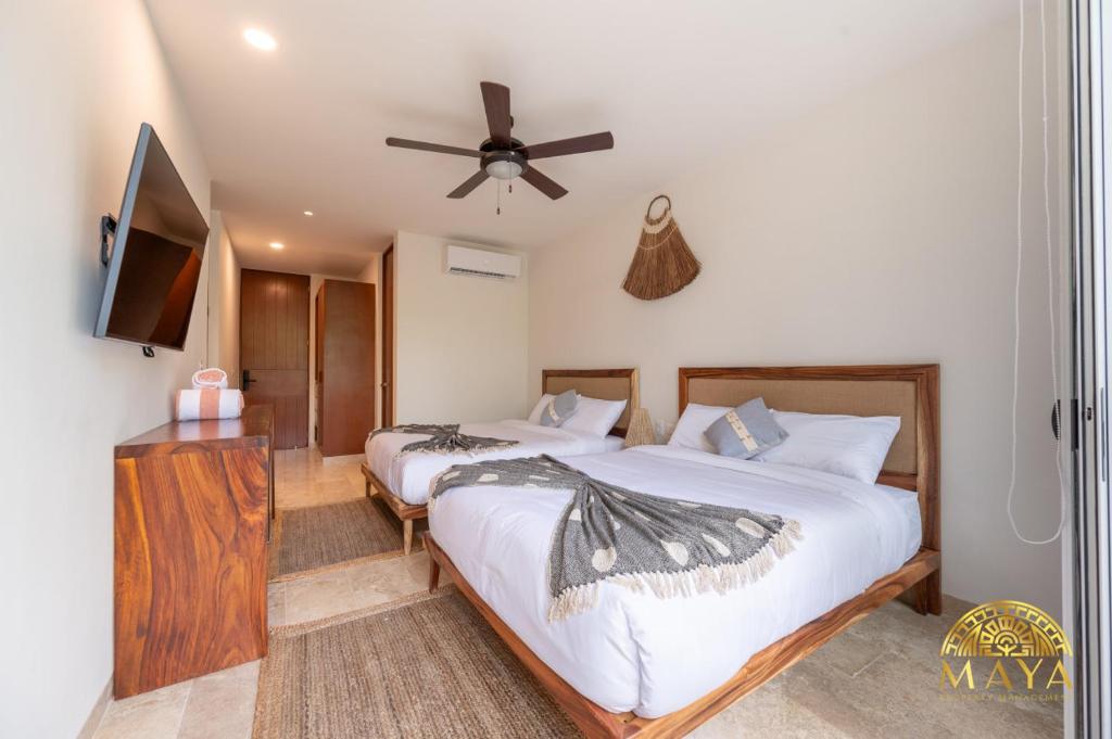 Un dormitorio con dos camas y un televisor de pantalla plana. en NHOA 208C Lux 1BR Condo Jungle View in Aldea Zama, en Tulum