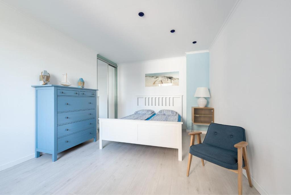een slaapkamer met een bed en een blauwe dressoir en een stoel bij Sopocki Apartament przy Plaży in Sopot