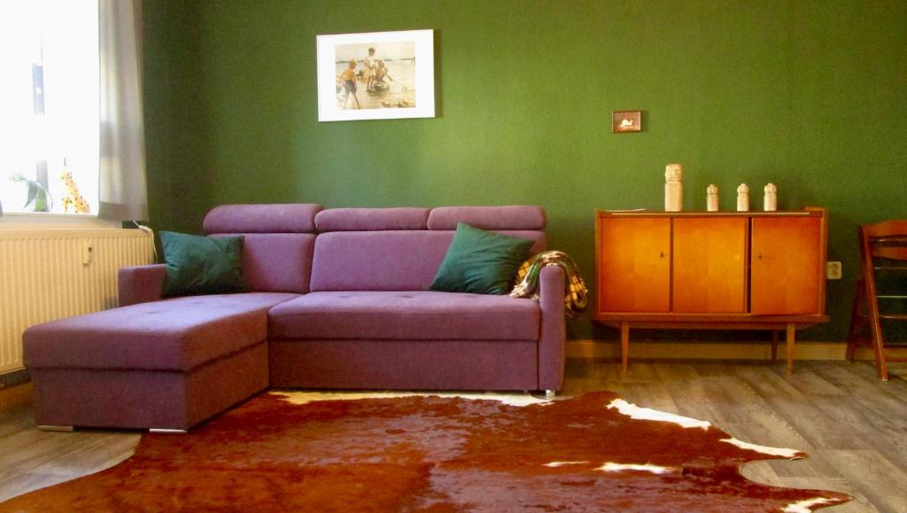 ein Wohnzimmer mit einem lila Sofa und grünen Wänden in der Unterkunft Ferienwohnung Ida Pfeiffer in Eibenstock