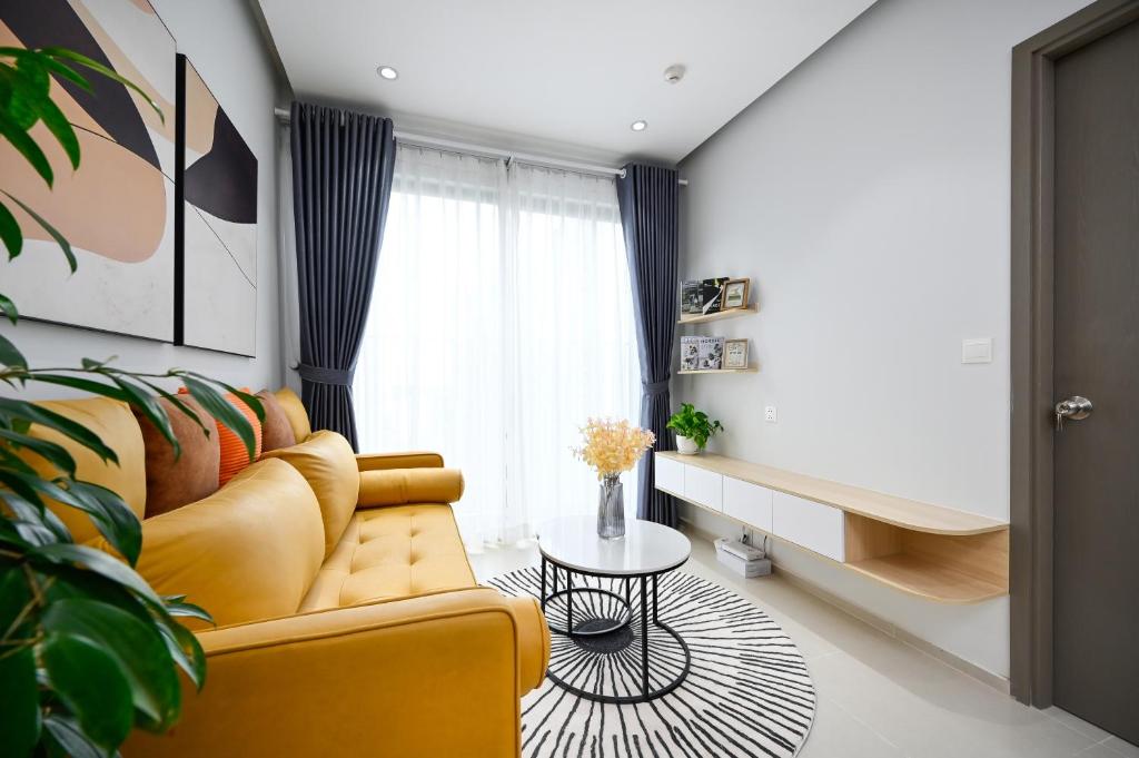a living room with a yellow couch and a table at Căn hộ Westgate- 2N House in Ho Chi Minh City