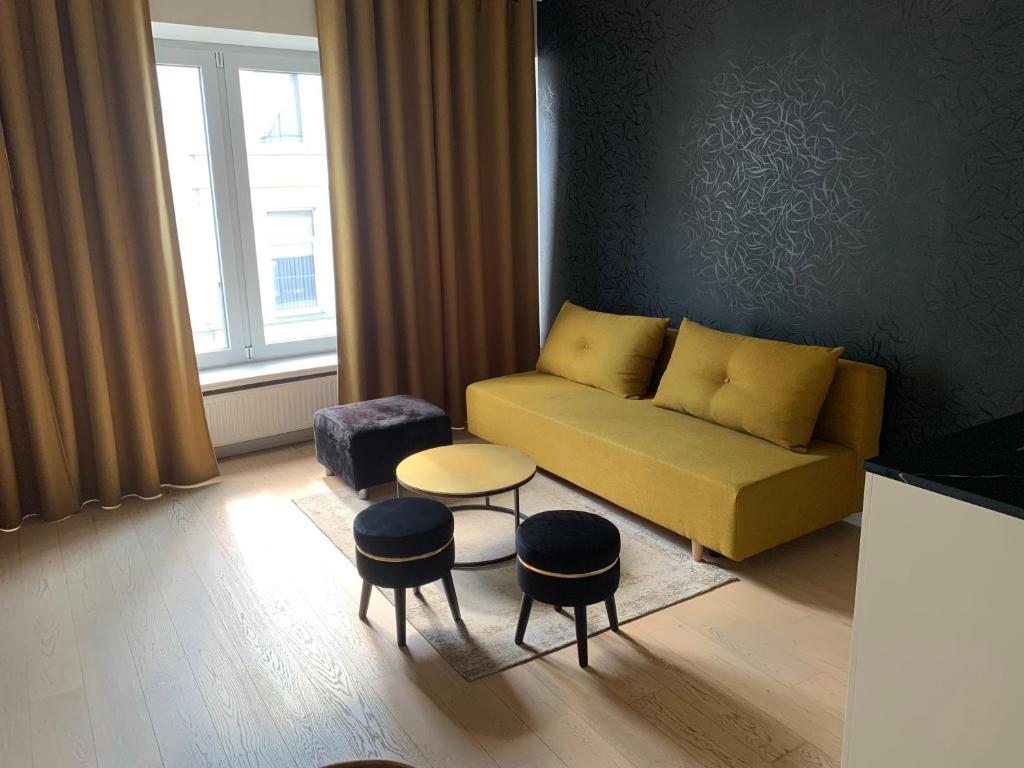 sala de estar con sofá amarillo y taburetes en Coco's en Amberes