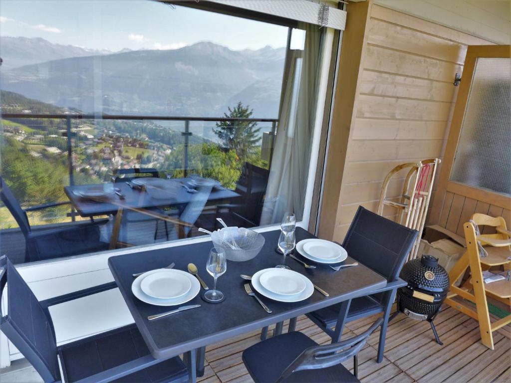 a dining table and chairs on a balcony with a view at Apartment Clair-Azur-2 by Interhome in Randogne