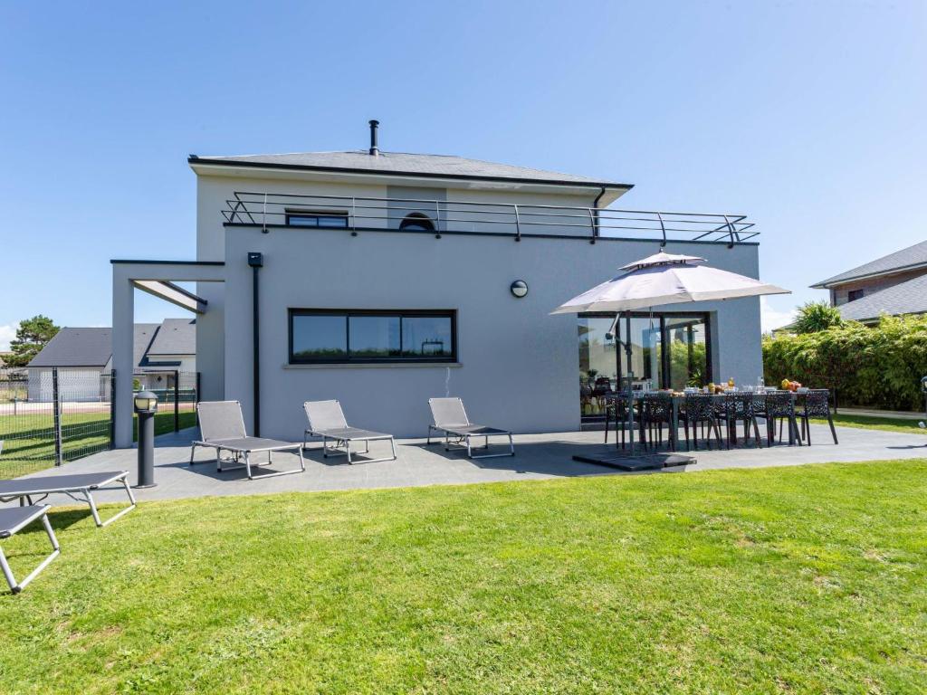 eine Terrasse mit Tisch und Stühlen und einem Sonnenschirm in der Unterkunft Holiday Home Pirou Beach by Interhome in Pirou