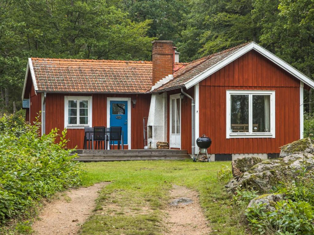 una pequeña casa roja con una puerta azul en Chalet Ängsjömåla by Interhome en Eringsboda