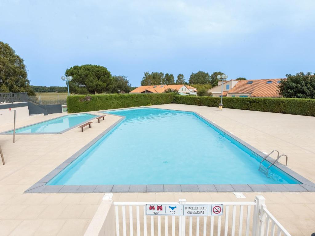 a large swimming pool with blue water at Holiday Home Les Charmilles-10 by Interhome in La Palmyre