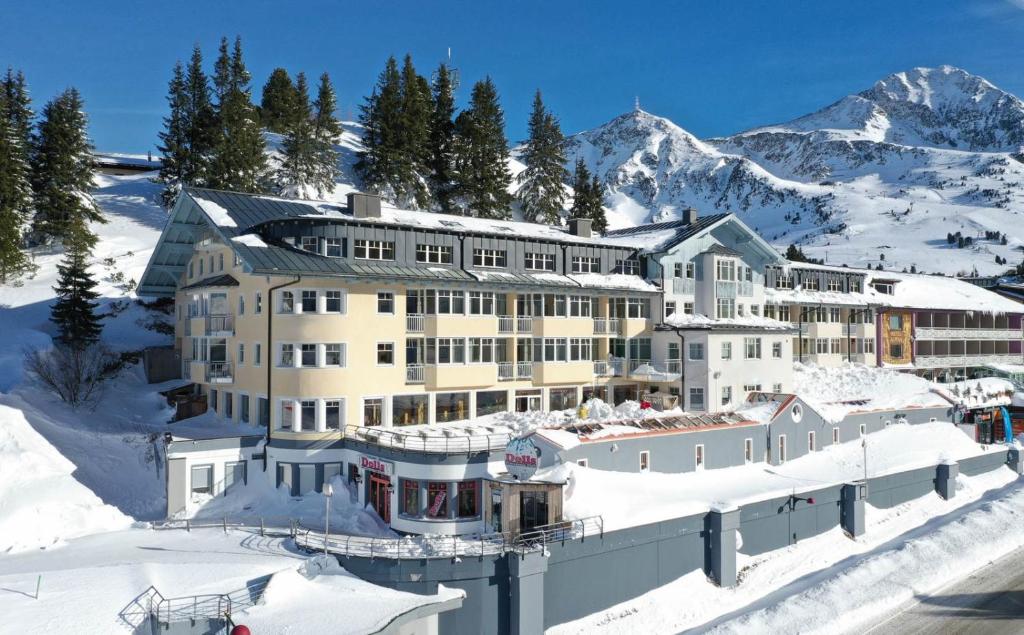 a large building in the snow with a mountain at Heart Hotel Aurora in Obertauern