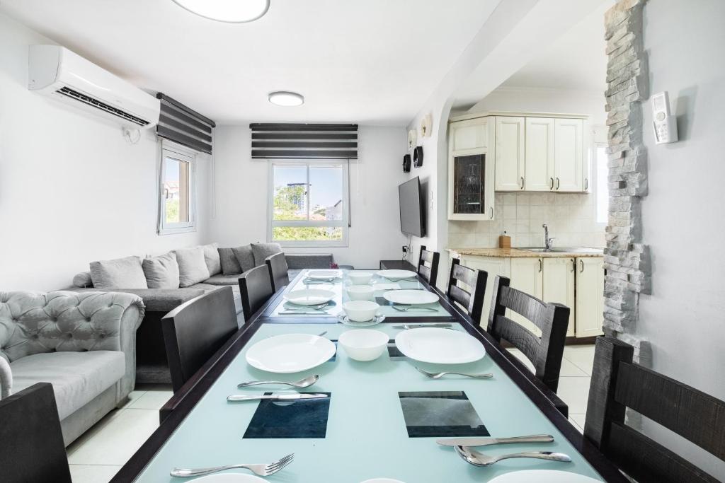 a dining room with a long table and a couch at relaxing duplex in ashdod by torohome in Ashdod