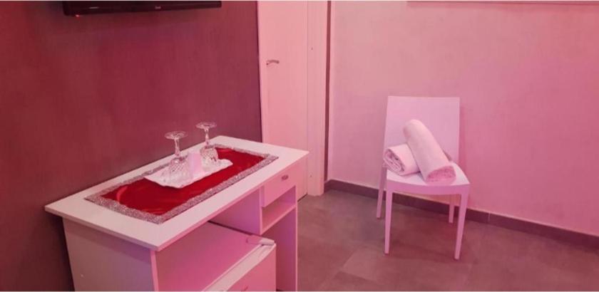 un bagno rosa con lavandino e sedia di Hotel taromy a Napoli