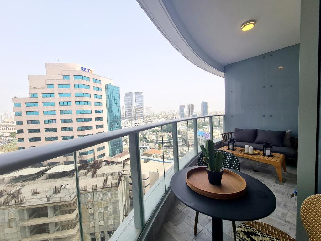 Gindi Tower Apartment - By Beach Apartments TLV في تل أبيب: بلكونه مع طاوله واطلاله على مدينه
