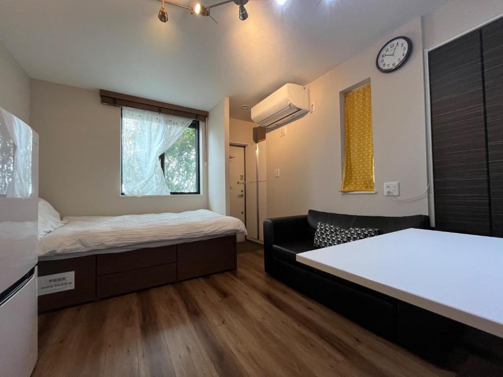 een kamer met 2 bedden en een bank en een klok bij Meguro-ku - House - Vacation STAY 8878 in Tokyo