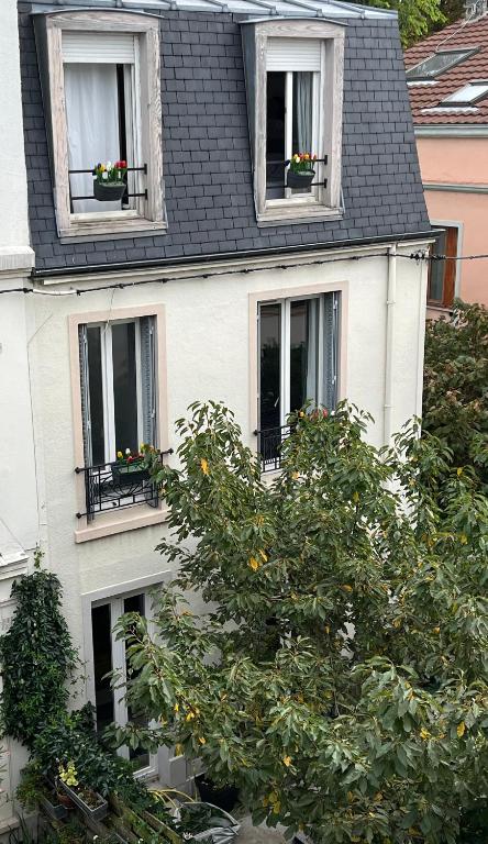 une maison blanche avec deux fenêtres et un oranger dans l'établissement Jolie maison de ville à 5 minutes de Paris pour 5 voyageurs parking inclus, à Clichy