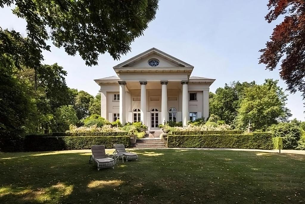 uma casa branca com duas cadeiras na relva em Leyselebeke Castle em Bruges