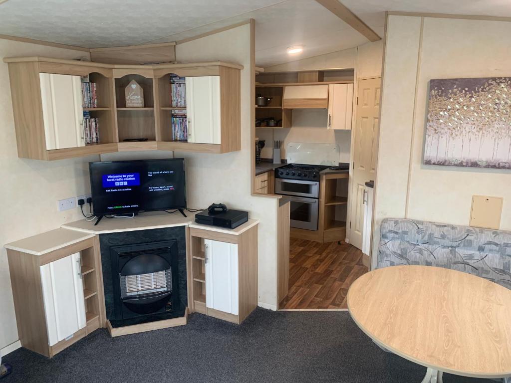 a small kitchen with a stove and a table at K&Ds Caravans in Chapel Saint Leonards