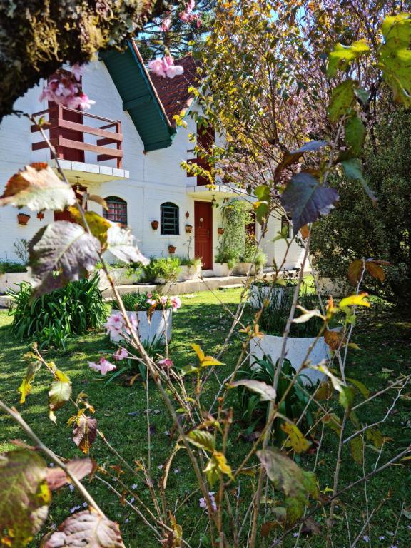 uma casa branca com uma porta vermelha num quintal em marcita chalé em Monte Verde