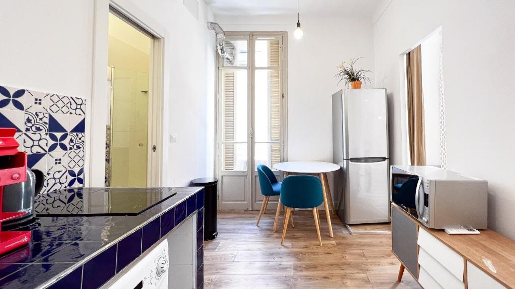 a kitchen with a refrigerator and a table with chairs at Appartement bleu l'union in Beausoleil