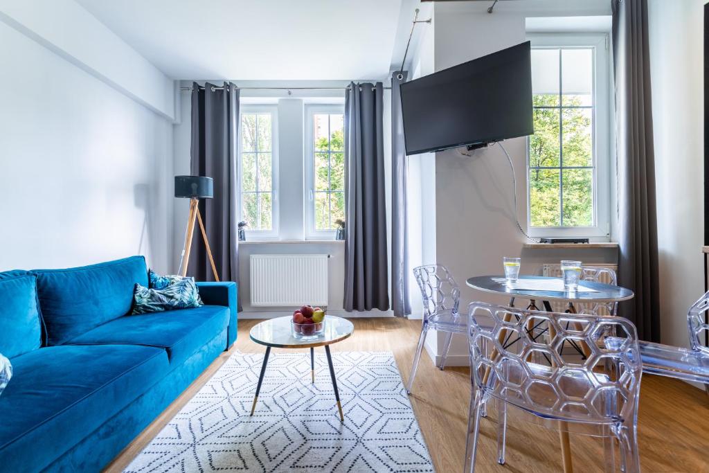 ein Wohnzimmer mit einem blauen Sofa und einem Tisch in der Unterkunft Victus Apartamenty Playa&Relax in Sopot