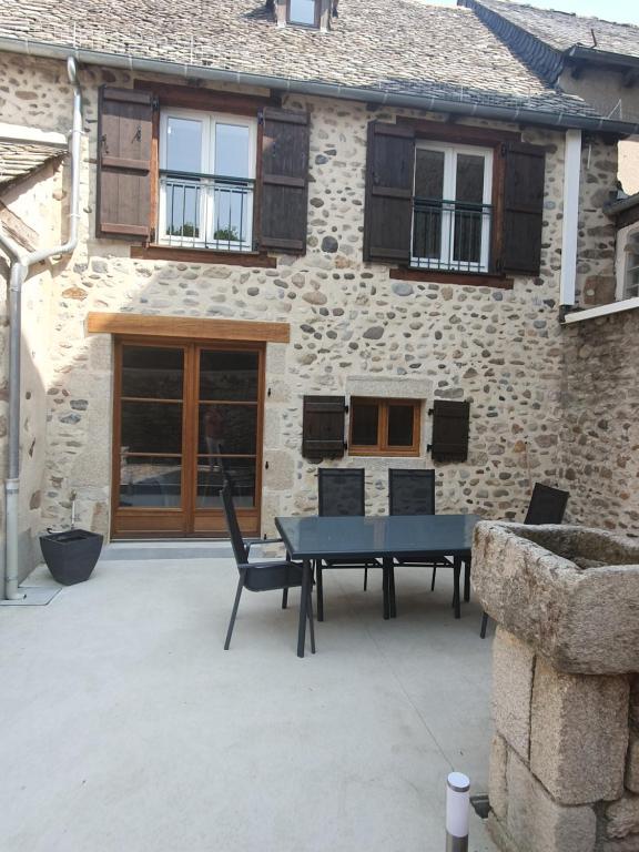 eine Terrasse mit einem Tisch und Stühlen vor einem Gebäude in der Unterkunft Les terrasses de Dordogne in Argentat