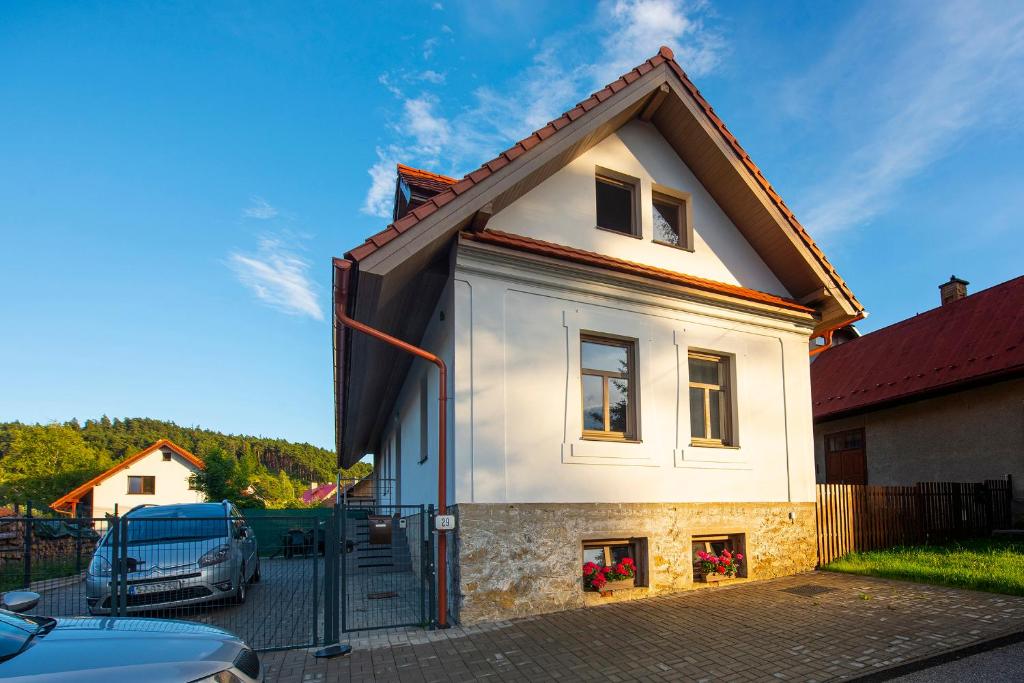 una pequeña casa blanca con techo rojo en Guest House Mengsdorf en Mengusovce