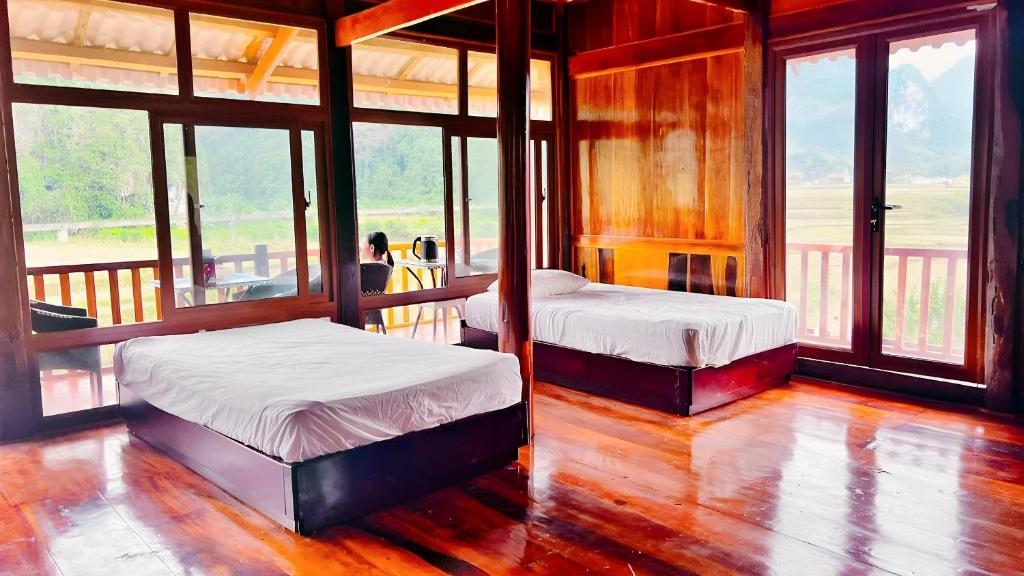 two beds in a room with large windows at Đồng Lâm Ecolodge Homestay in Hữu Lũng