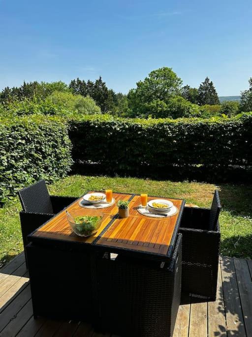 une table en bois avec deux assiettes de nourriture dans l'établissement 7mn de Deauville Jardin Wifi Box TV, à Saint-Arnoult