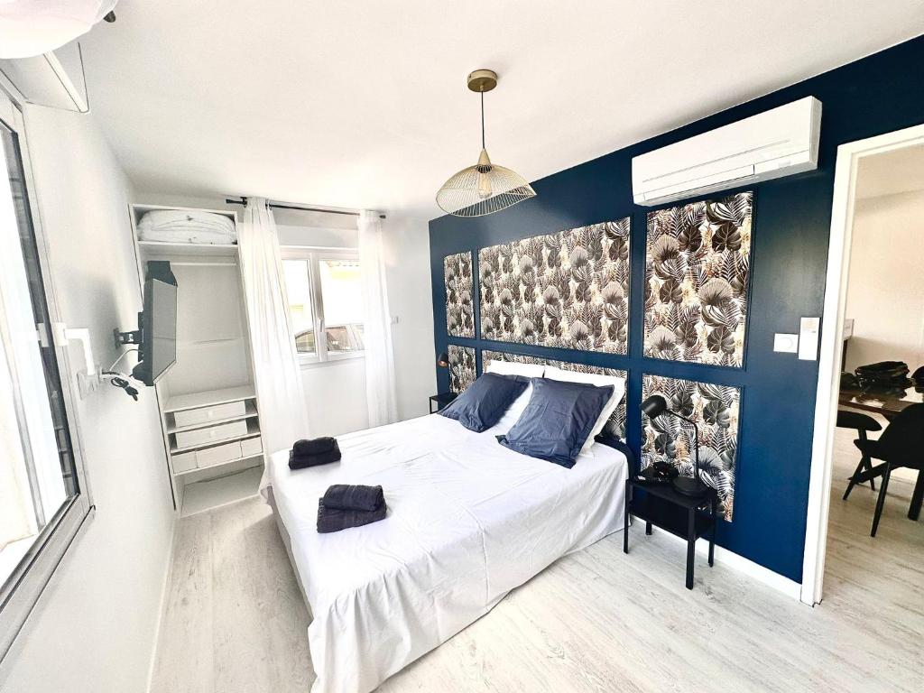 une chambre avec un lit et un mur bleu dans l'établissement Oasis de Thau, à Balaruc-les-Bains