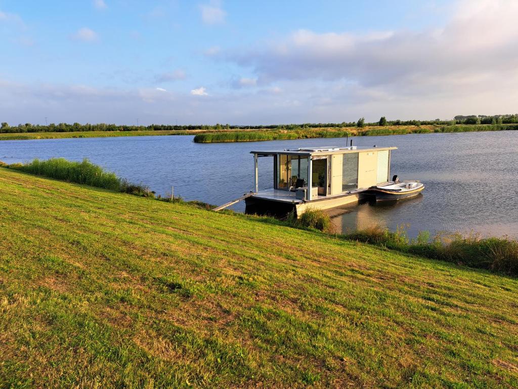 a small house on a dock on a lake at AquaHome - NP de Biesbosch - Bijzonder overnachten op een houseboat! in Werkendam