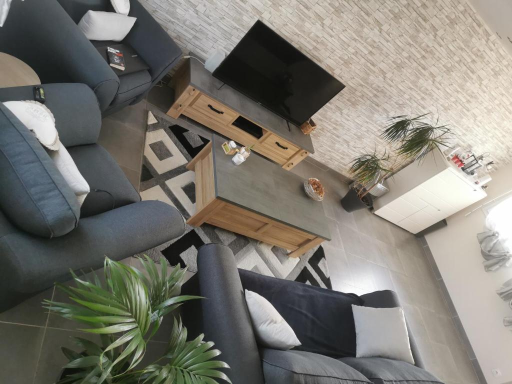 einen Blick über ein Wohnzimmer mit 2 blauen Stühlen und einem TV in der Unterkunft Maison avec jardin in Plouigneau