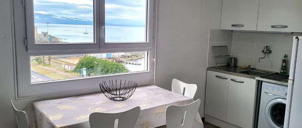 una cucina con un tavolo con sedie e una finestra di Appartement entier, climatisé, vue mer ad Ajaccio