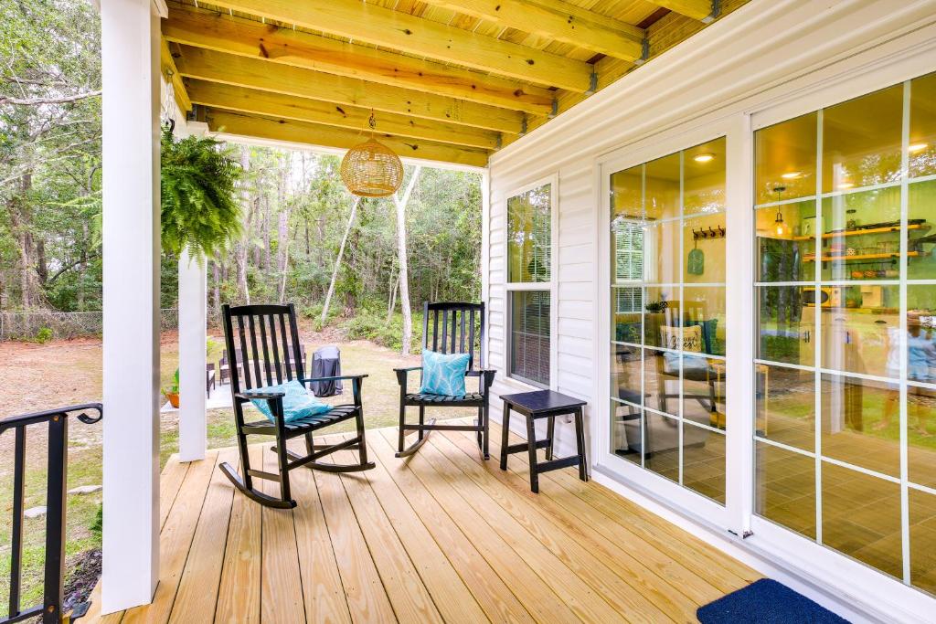 a screened porch with two chairs and a chandelier at Cozy Cottage Minutes to Downtown Southport! in Southport