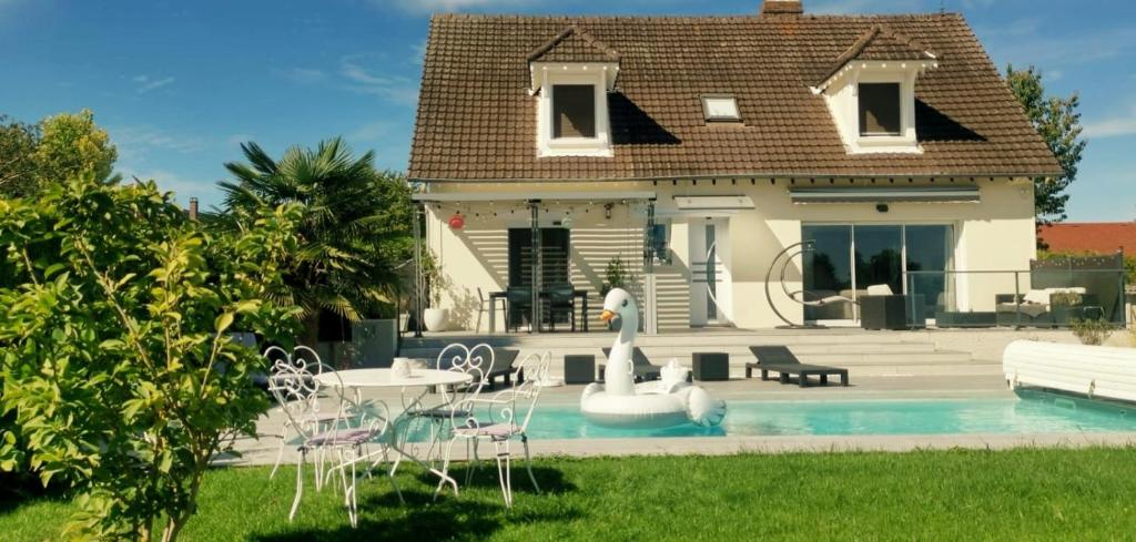 een huis met een zwembad met stoelen en een fontein bij Ma Douce Bulle Piscine & Détente in Saint-Léger-près-Troyes