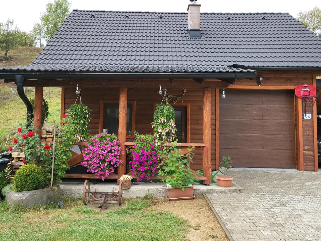 a wooden house with flowers in front of it at Chata Hriňová in Hriňová