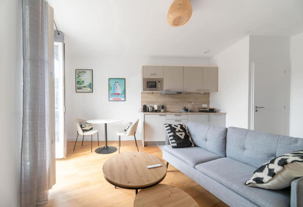 - un salon avec un canapé bleu et une table dans l'établissement Le Royal - Appartement design - Hyper centre, à Vichy