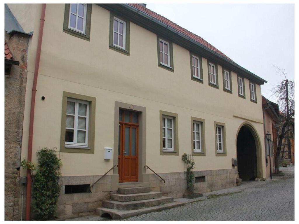 a yellow house with a red door on a street at Stadthaus in Mellrichstadt